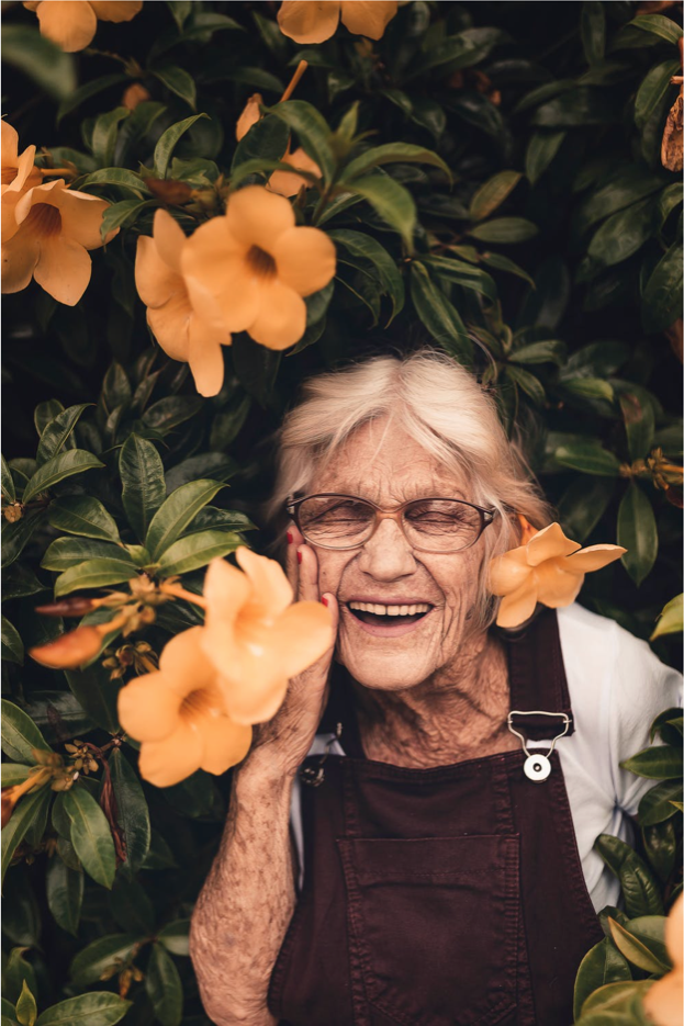 elderly woman next to flowering tree