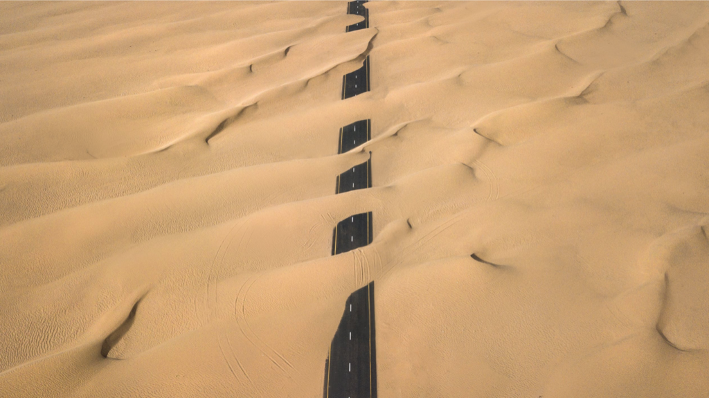 Desert partially covering 2-lane road - aerial view